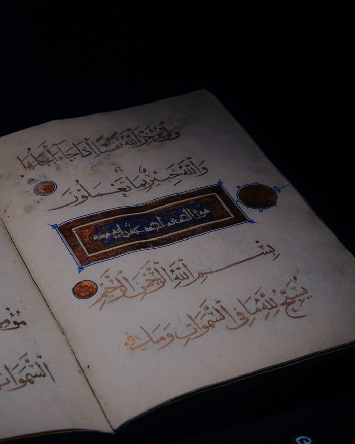 Open Quran page with intricate Arabic script and ornamentation, symbolizing Islamic faith and scripture.