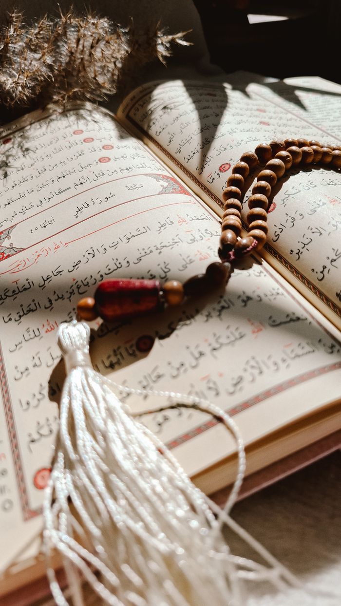 A Quran with prayer beads resting on it, bathed in warm natural sunlight.